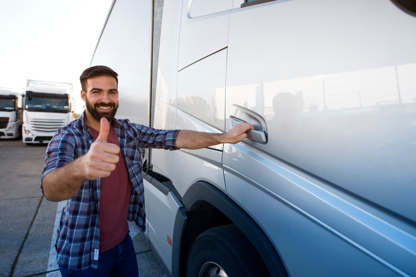 Truck driver giving a thumbs up next to his trailer